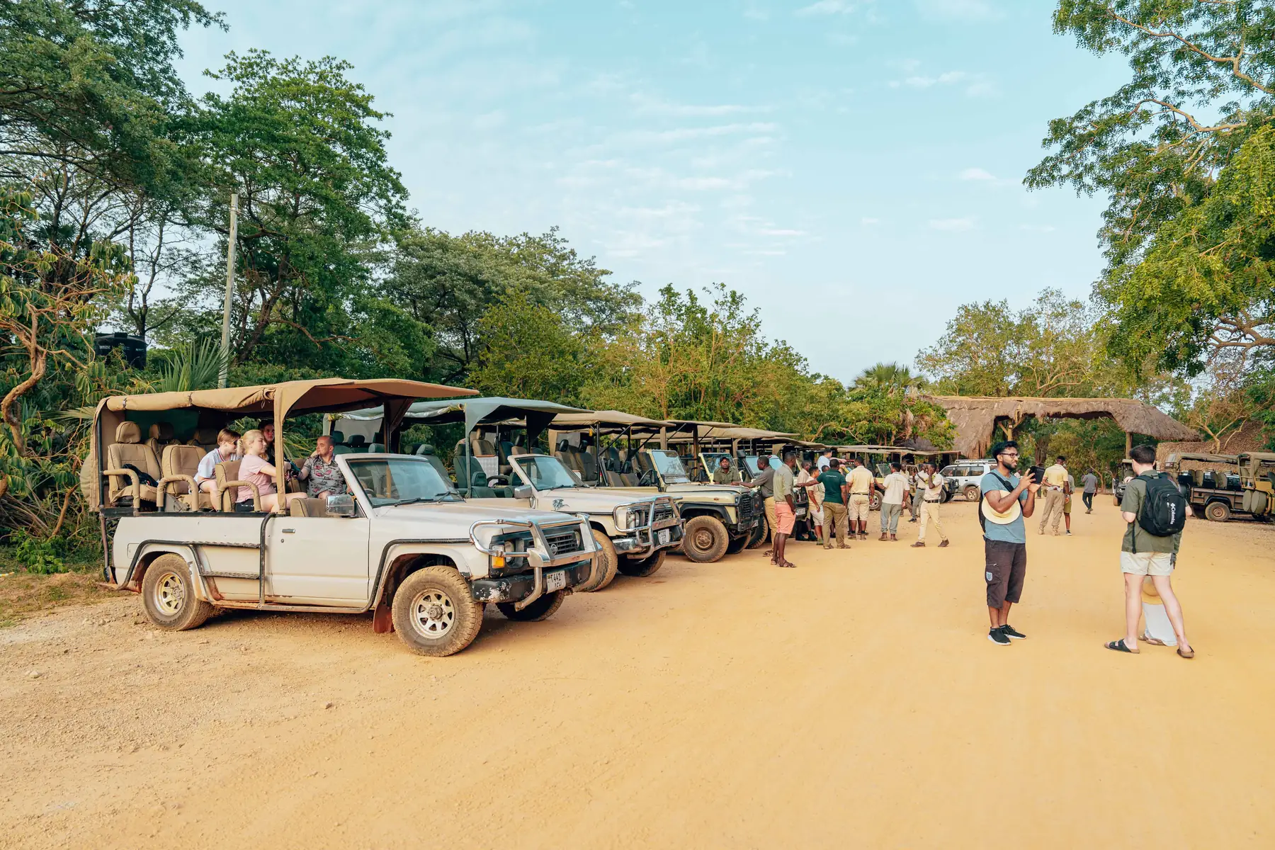 Guests boarding open-top 4x4 safari vehicles on a dirt road