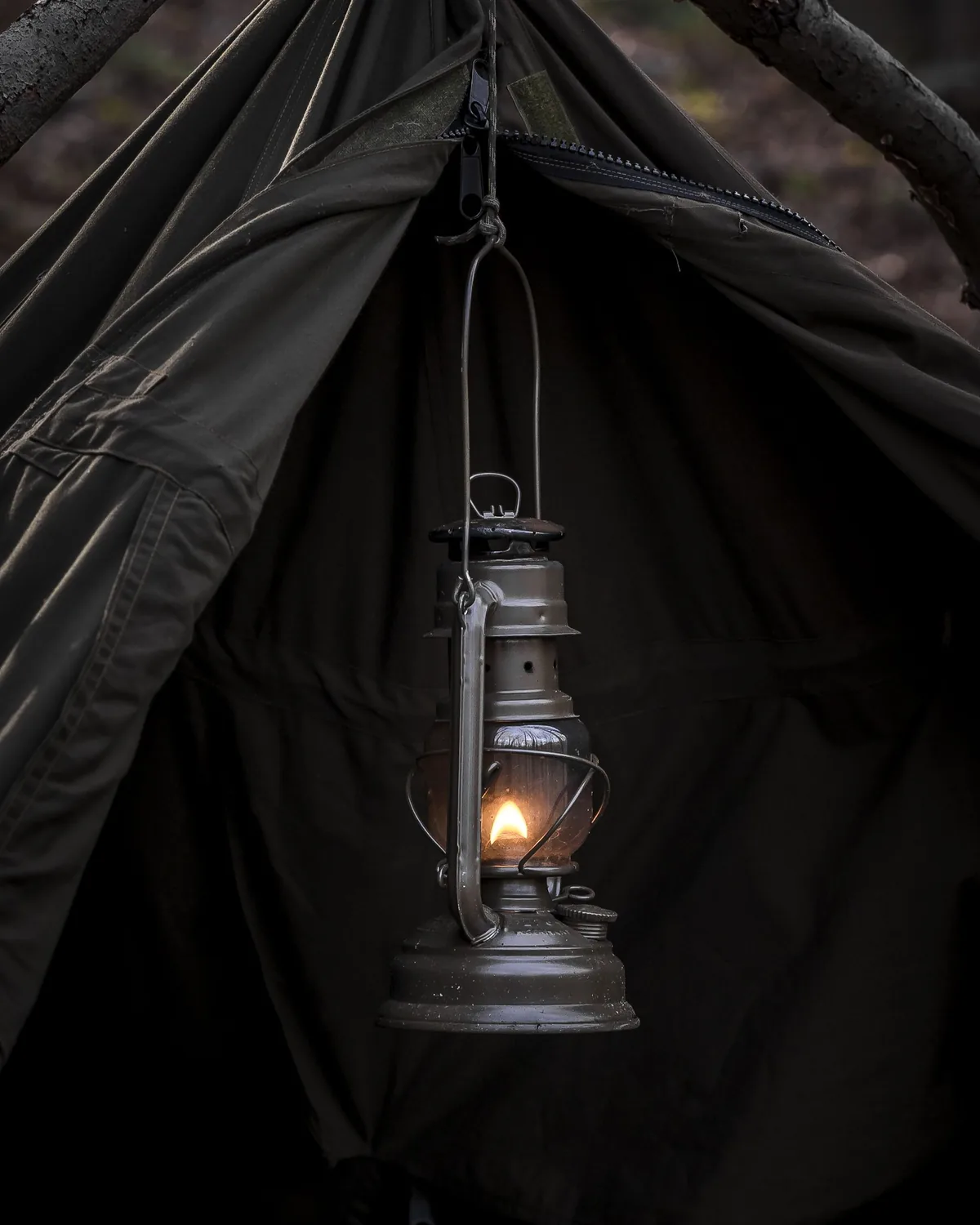 Lantern hanging at the entrance of a safari tent at dusk