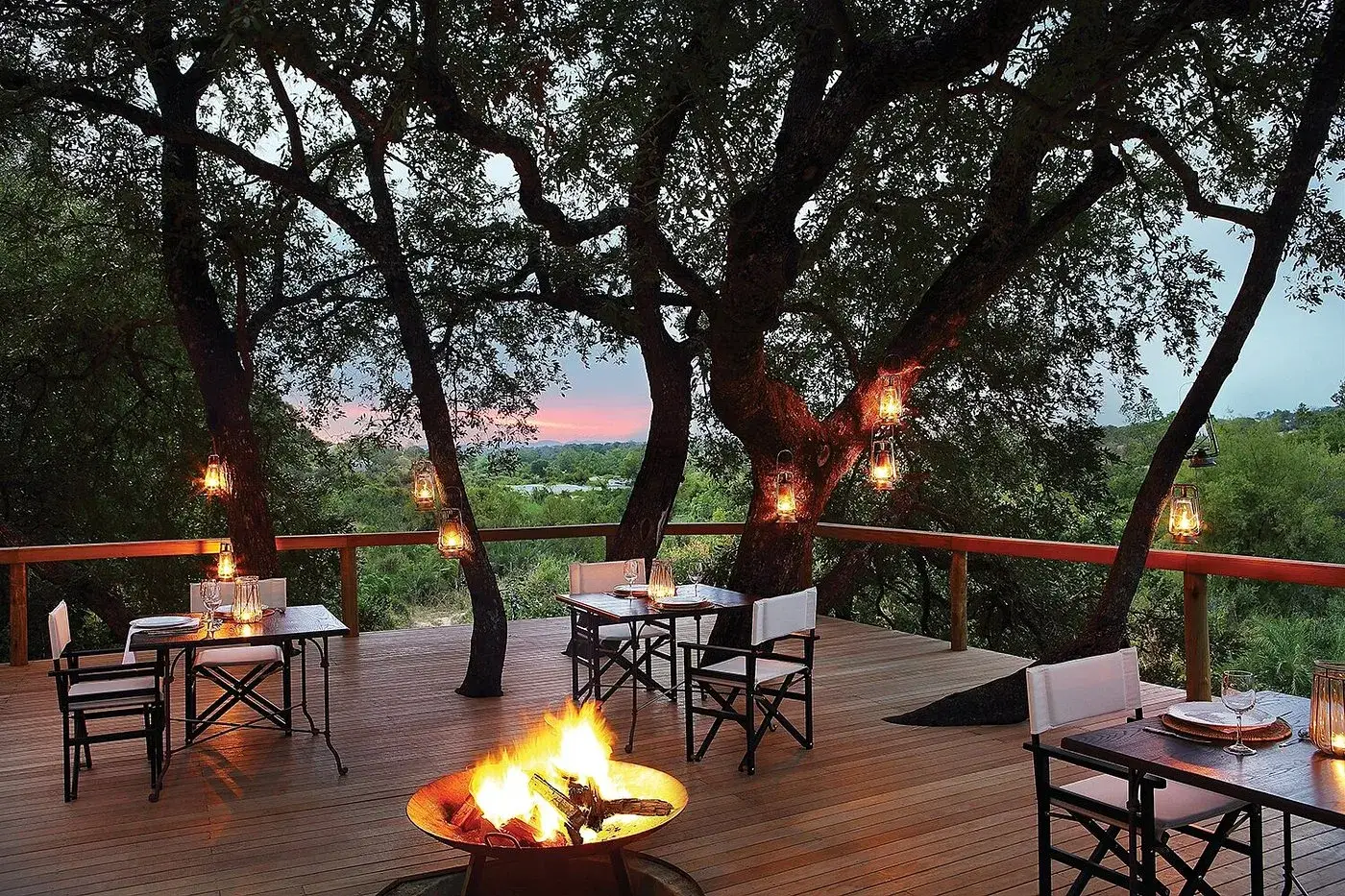 Lanterns in the trees and a fire on the deck at Londolozi Tree Camp at dusk, Sabi Sand, South Africa
