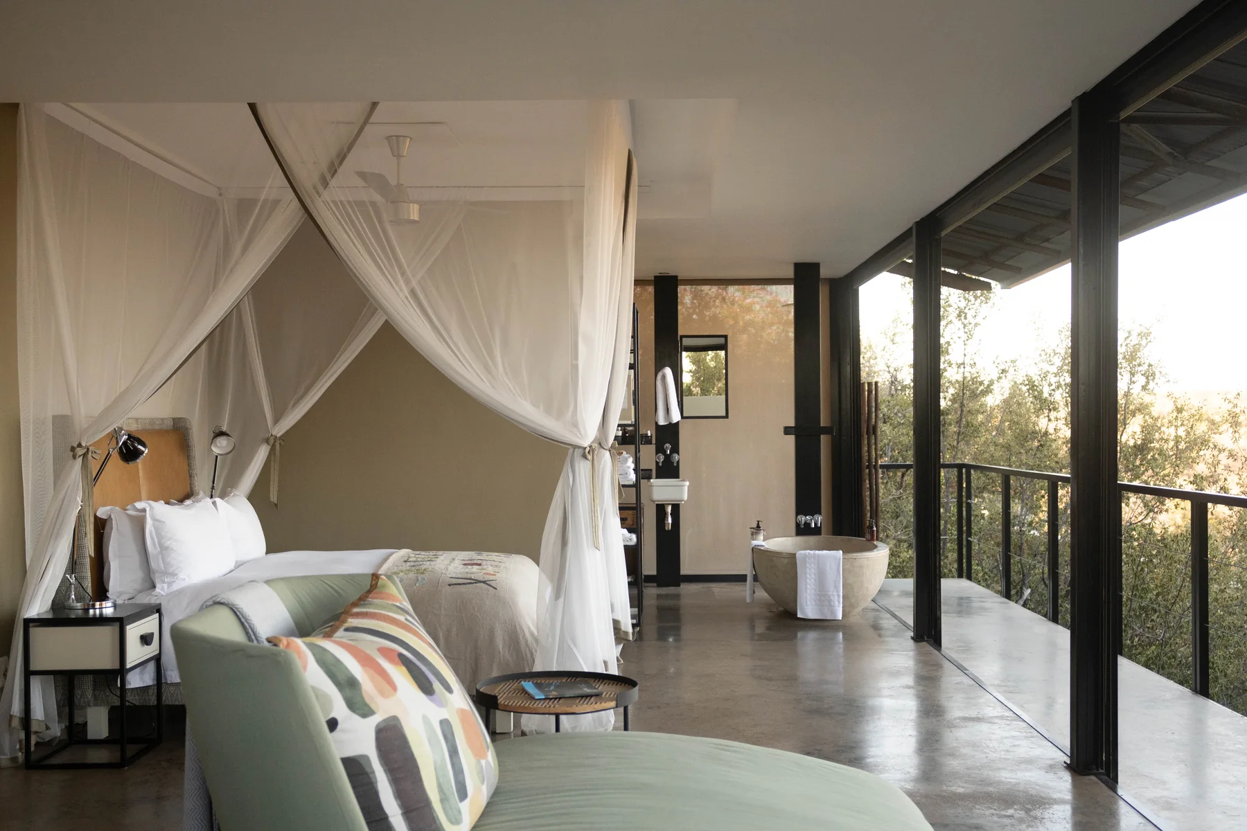 Interior of a luxury safari tent in Tanzania with a canopied bed and a view over the bush