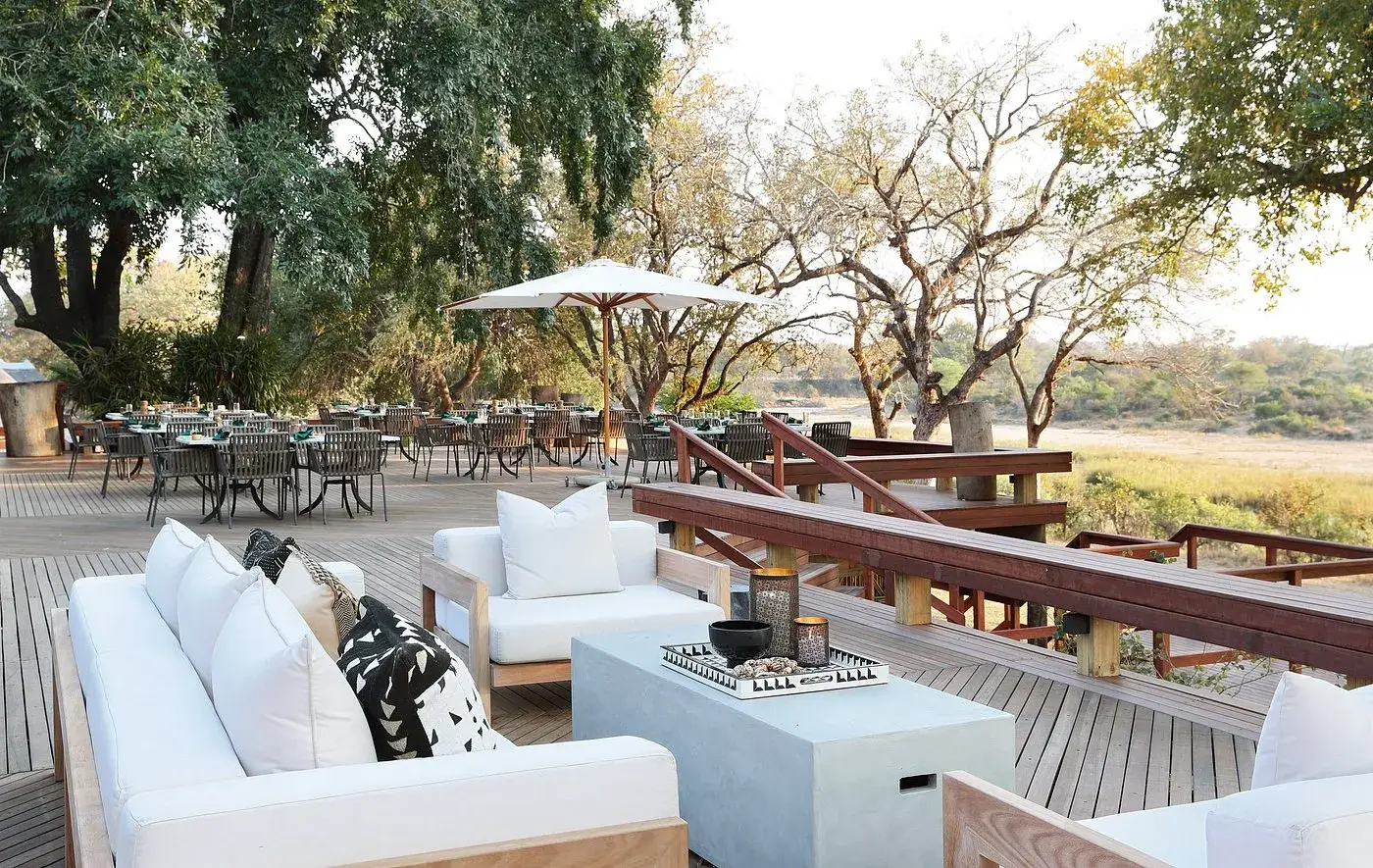 The open deck and dining area at MalaMala, shaded by large trees above the Sand River, South Africa