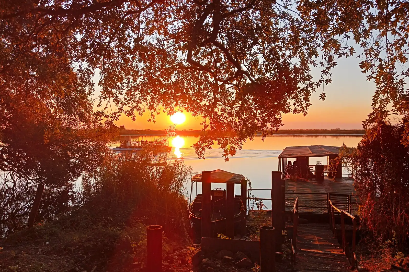 Sunset over the water at Moremi with boats moored at a jetty, Botswana