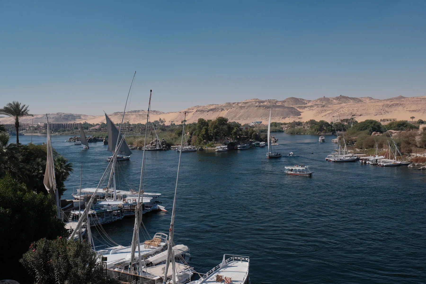 Feluccas and cruise boats on the Nile at Aswan with the desert escarpment behind, Egypt