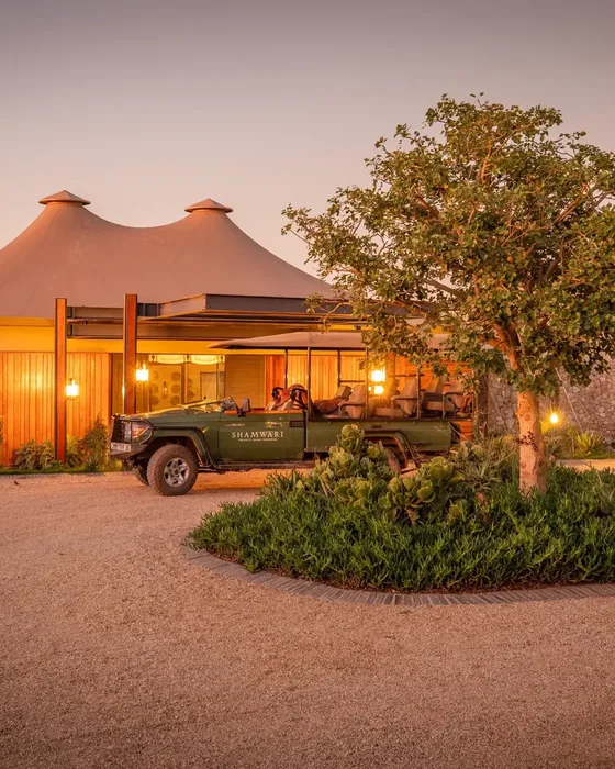 An owner-run safari lodge with a game-drive vehicle waiting at the entrance