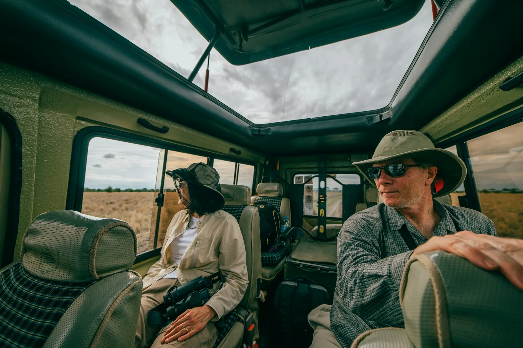 An older couple on a game drive in a pop-up roof safari vehicle